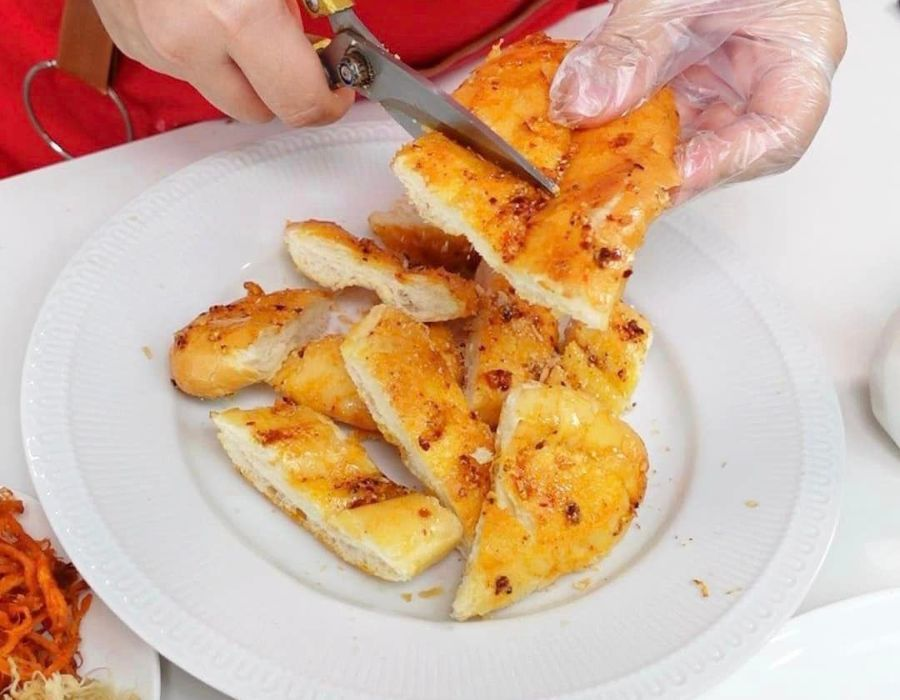 Bước 3: Cán bánh mì sao cho dẹp ra theo mặt phẳng của giấy.
Bước 4: Chuẩn chảo nóng sau đó quét bánh mì đã cán theo nước sốt đã được chuẩn bị ở bước 2. Đặt bánh mì lên chảo nóng, để bếp nhỏ lửa, lật bánh mì đều tay. Sau khi phần vỏ bánh áo bên ngoài nước sốt bắt đầu keo lại và bánh mì giòn đều. Hãy lấy chúng ra chiếc dĩa và cắt những miếng vừa ăn.