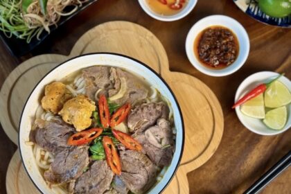 Cho hành tây, gừng đập dập, thơm, ớt xanh, sả cây vào nồi nước rồi bắt lên bếp đun cho đến khi nước sôi thì bắt đầu cho bắp bò, giò heo, xương ống bò vào nấu chung. Đun sơ qua khoảng 3-5 phút để khử mùi hôi của thịt, sau đó vớt ra rửa thật sạch với nước. Kế tiếp chuẩn bị tỏi và hành băm xào cho thơm cho xương ống và giò heo xào sơ. Sau đó cho nước sôi đun rồi nêm gia vị vào 1/2 muỗng canh muối, 2 muỗng đường phèn, 3 muỗng canh nước mắm và 80g mắm ruốc, khuấy đều và nêm lại để cho vừa khẩu vị với bạn. Nhớ vớt bọt trong quá trình đun, sau đó hạ nhỏ hầm và cho thêm bắp bò và giò heo đã rửa đun đến khi chín. Tiếp đó vớt bắp bò và giò heo ra.