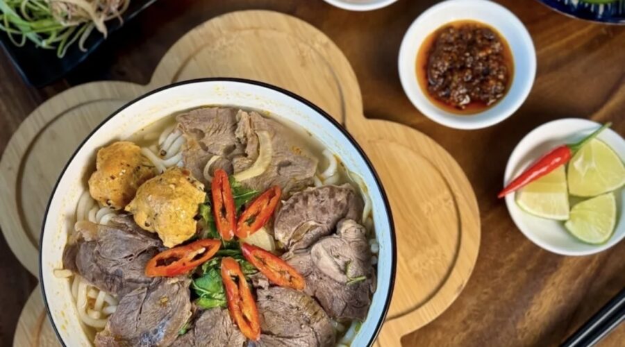 Cho hành tây, gừng đập dập, thơm, ớt xanh, sả cây vào nồi nước rồi bắt lên bếp đun cho đến khi nước sôi thì bắt đầu cho bắp bò, giò heo, xương ống bò vào nấu chung. Đun sơ qua khoảng 3-5 phút để khử mùi hôi của thịt, sau đó vớt ra rửa thật sạch với nước. Kế tiếp chuẩn bị tỏi và hành băm xào cho thơm cho xương ống và giò heo xào sơ. Sau đó cho nước sôi đun rồi nêm gia vị vào 1/2 muỗng canh muối, 2 muỗng đường phèn, 3 muỗng canh nước mắm và 80g mắm ruốc, khuấy đều và nêm lại để cho vừa khẩu vị với bạn. Nhớ vớt bọt trong quá trình đun, sau đó hạ nhỏ hầm và cho thêm bắp bò và giò heo đã rửa đun đến khi chín. Tiếp đó vớt bắp bò và giò heo ra.