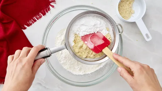 Bước 1: Ray đường icing sugar và bột hạnh nhân vào một tô lớn rồi trộn đều.
Bước 2: Cho hỗn hợp này vào máy xay rồi mang ra ray lại một lần nữa. Lặp lại quá trình này 2 lần để tạo ra lớp vỏ bánh macaron được mịn màng đẹp.