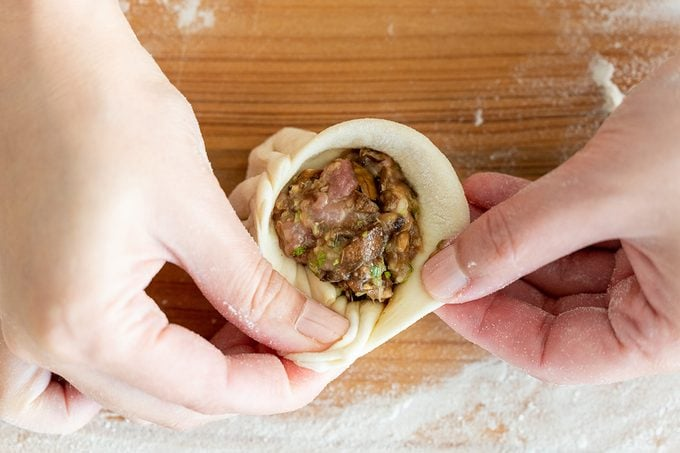 Bước 3: Tạo Hình Bánh Bao
Chia bột: Sau khi bột đã nở, chia bột thành các viên nhỏ khoảng 30g mỗi viên.
Nặn vỏ bánh: Lăn từng viên bột thành hình tròn, rồi dùng tay ấn dẹt một chút để dễ dàng gói nhân.
Cho nhân vào: Lấy một lượng nhân vừa đủ cho vào giữa vỏ bánh. Gói kín vỏ bánh lại sao cho nhân không bị rơi ra ngoài. Chú ý túm phần trên của vỏ bánh để tạo hình đẹp mắt.
Ủ bánh: Đặt bánh lên giấy nến hoặc khuôn bánh bao, đậy kín lại và để bánh nghỉ trong khoảng 30 phút để bánh nở đều.