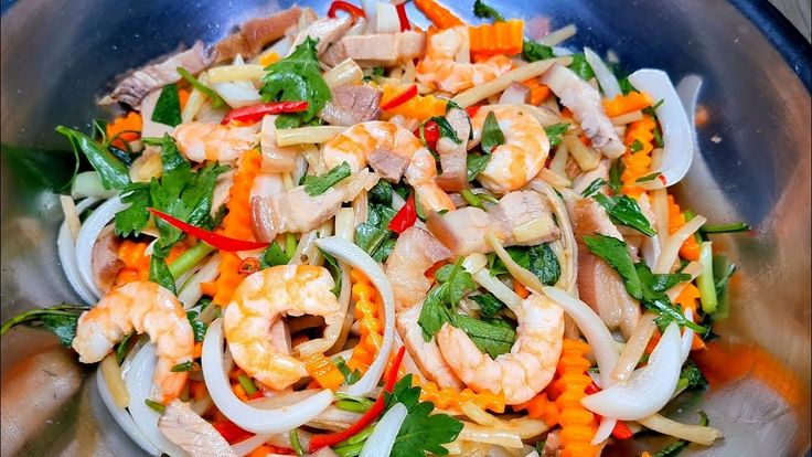 Bước 1: Trộn nguyên liệu
Cho ngó sen, cà rốt, hành tây vào tô lớn.
Thêm tôm, thịt đã sơ chế vào.
Rưới từ từ nước trộn gỏi đã pha, trộn nhẹ tay để không làm gãy nguyên liệu.
Cuối cùng cho rau thơm vào trộn đều.