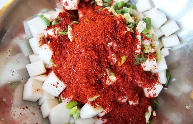 Bước 6: Trộn Củ Cải Với Gia Vị
Trộn đều: Cho củ cải đã ráo nước vào tô gia vị, dùng tay (đeo găng tay nilon để tránh cay) trộn đều cho đến khi gia vị bao phủ đều các miếng củ cải.
Thêm hành lá: Cuối cùng, cho hành lá cắt khúc vào và trộn đều.