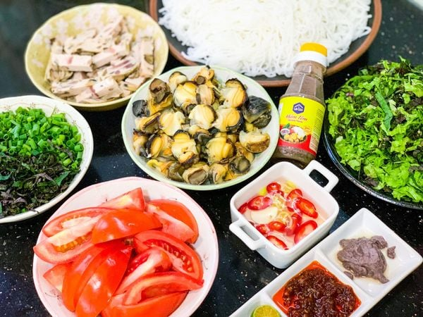 Nguyên Liệu Nấu Bún Ốc (Cho 4-5 Người)

Phần ốc:

Ốc nhồi: 1kg (chọn con to, vỏ bóng, miệng đầy)

Nước vo gạo: 1-2 lít

Ớt tươi: 1-2 quả (thái lát)

Giấm hoặc bỗng rượu: 1-2 thìa canh

Phần nước dùng:

Xương ống lợn: 600g

Cà chua: 200g (cắt múi cau)

Dấm bỗng nếp: 150ml

Gia vị: Muối, hạt nêm, nước mắm, mì chính (tùy chọn)

Phần ăn kèm:

Bún sợi to: 800g

Rau sống: Tía tô, xà lách, giá đỗ, hoa chuối (tùy chọn)

Hành lá: 2-3 cây (thái nhỏ)

Ớt tươi: 1-2 quả (thái lát)

Phần nước chấm:

3 muỗng canh mắm tôm (ưu tiên mắm tôm Thanh Hóa, có màu tím, thơm và vị ngọt nhẹ)

1 muỗng cà phê đường

1 muỗng cà phê rượu trắng (giúp khử mùi nồng của mắm tôm)

1 quả chanh hoặc 2 quả tắc

3 quả ớt tươi (có thể thái lát hoặc xay nhuyễn)

1 củ hành tím

2 muỗng canh dầu ăn