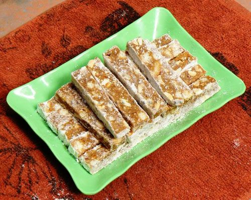 Bước 4: Tạo Hình Chè Lam
Sau 20 phút, cho khối bột ra bàn sạch, rắc chút bột khô để chống dính rồi dùng cây cán bột cán cho miếng bột hơi dày.
Dùng dao cắt bột thành những miếng vừa ăn rồi lăn từng miếng bánh qua bột nếp khô.
Để chè lam nguội hẳn rồi bảo quản trong hộp kín, để nơi khô ráo, thoáng mát.