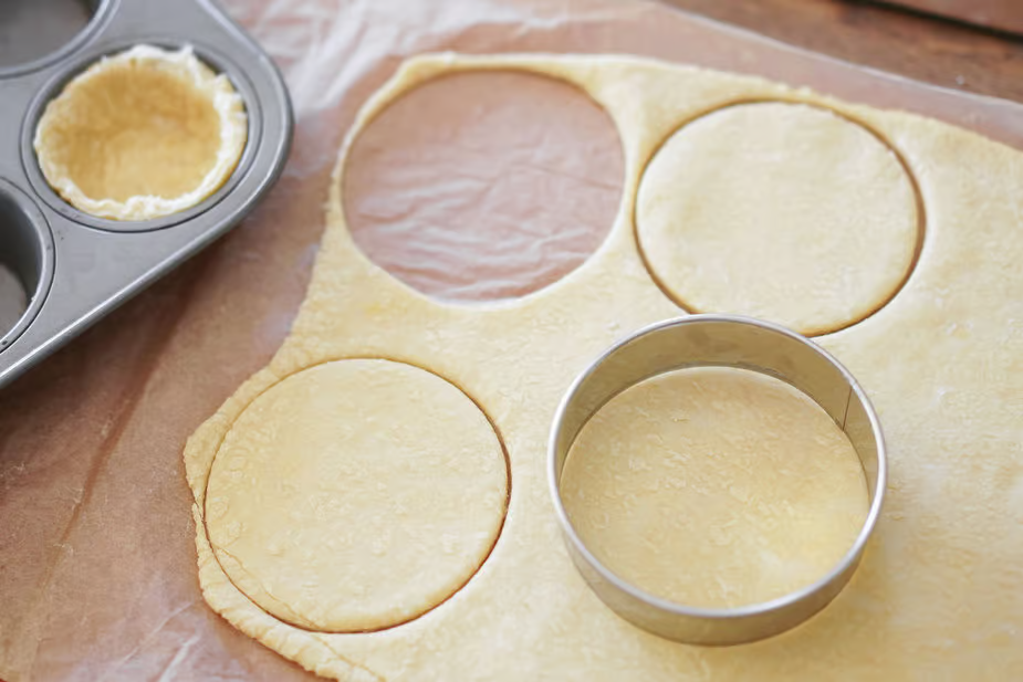 Định hình vỏ bánh: Cắt bột thành hình tròn vừa khuôn tart, đặt vào khuôn và ấn nhẹ để bột dính chặt. Dùng nĩa chọc vài lỗ nhỏ dưới đáy để tránh vỏ bánh phồng lên khi nướng.