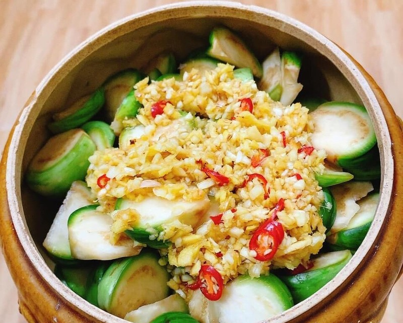 Hướng dẫn cách làm cà bát muối xổi
Sơ chế cà bát: Cà bát rửa sạch, cắt bỏ cuống và bổ múi cau. Ngâm cà vào nước muối loãng trong 20 phút để loại bỏ nhựa và không bị thâm đen.
Chuẩn bị gia vị: Riềng gọt vỏ, rửa sạch, một nửa thái chỉ, nửa còn lại cắt miếng nhỏ. Tỏi bóc vỏ, ớt bỏ cuống và băm nhuyễn. Trộn riềng thái chỉ, tỏi và ớt vào máy xay nhuyễn hoặc băm nhỏ.
Pha nước muối: Trộn đều đường, tương ớt, giấm, muối và nước lọc cho đến khi đường và muối tan hết.
Muối xổi cà: Cho cà vào bát lớn, đổ hỗn hợp nước muối đã pha vào và trộn đều. Để cà ngấm gia vị khoảng 5 phút, sau đó đảo lại một lần nữa. Đậy kín bát và cho vào ngăn mát tủ lạnh khoảng 30 phút là có thể thưởng thức.
Thành phẩm: Cà muối xổi có vị chua ngọt vừa phải, giòn tan và hương thơm đặc trưng từ riềng, tỏi và ớt, rất thích hợp ăn kèm với cơm trắng hoặc các món mặn.