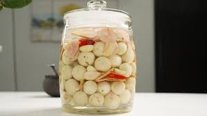 Bước 4: Xếp Cà và Gia Vị Vào Hũ
Chuẩn bị hũ: Chọn hũ thủy tinh hoặc sành, rửa sạch và tráng qua nước sôi để tiệt trùng.
Xếp cà: Xếp một lớp cà vào đáy hũ, sau đó thêm một lớp riềng, tỏi và ớt. Tiếp tục xếp xen kẽ các lớp cho đến khi hết nguyên liệu.
Đổ nước muối: Đổ nước muối đã nguội vào hũ sao cho ngập hoàn toàn cà pháo.
Nén cà: Dùng vỉ nan tre hoặc vật nặng để nén cà xuống, tránh để cà nổi lên trên mặt nước, giúp cà không bị thâm đen và lên men đều.