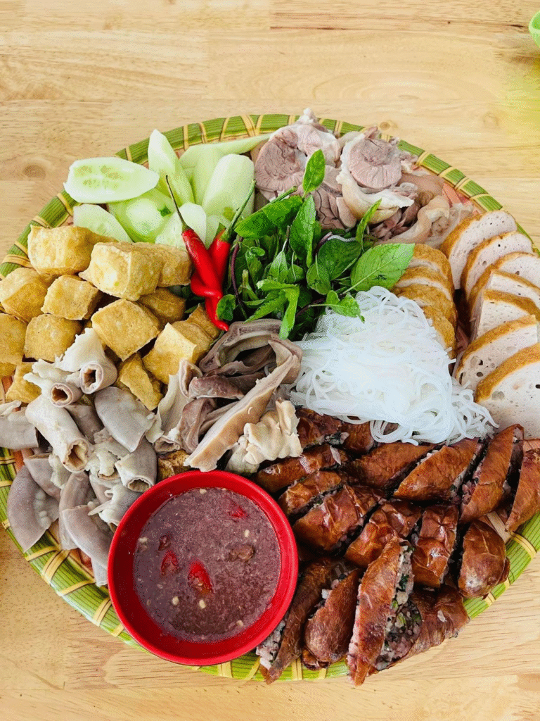 🍽 Bước 5: Trình bày & thưởng thức
Trải mẹt tre hoặc khay lớn, lót lá chuối (tạo cảm giác dân dã, đẹp mắt).
Xếp theo thứ tự: bún, đậu phụ, thịt luộc, chả cốm, nội tạng nếu có, rau thơm và chén mắm tôm chính giữa.
Thưởng thức: lấy bún + đậu + thịt cuộn rau, chấm mắm tôm. Từng vị hòa quyện thơm ngon, “bắt vị” và dễ gây nghiện.