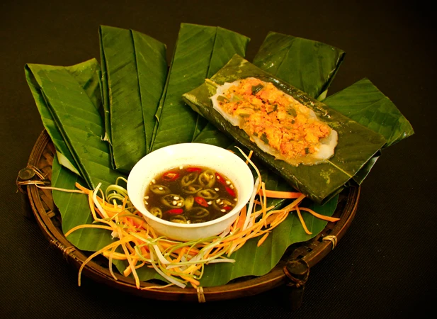 Yêu Cầu Thành Phẩm & Mẹo Nhỏ để làm món bánh nậm
Thành phẩm: Bánh được gói đẹp mắt, lớp ngoài của vỏ bánh trắng mịn, mềm vừa phải, phần nhân bên trong vừa thơm, vừa miệng; lá chuối ở bên ngoài thì giữ mùi thơm nhẹ quyện vào bánh .
Thưởng thức: Dùng nguyên bánh cùng nước chấm, thưởng thức chậm để cảm nhận vị ngọt của bột, vị thơm mặn mà của tôm – thịt quyện cùng mùi lá chuối.
Mẹo hay:
Nên phải trụng sơ lá chuối qua nước nóng để trong lúc gói bánh sẽ dễ gói.
Gói bánh vừa, không quá dày bột để bánh nhanh chín và mềm.
Hấp bằng lửa vừa, tránh lửa to làm bánh bị phình