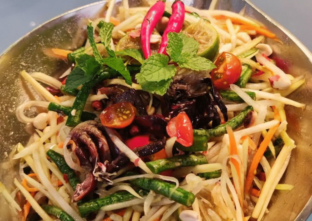 Gỏi đu đủ là món ăn phổ biến trong ẩm thực Đông Nam Á, đặc biệt là Thái Lan và các vùng có người Hoa.

Ba khía (hay còn gọi là baba, ka-pi, kapi prawns) là loại hải sản nhỏ, thân hình dẹp, thường sống ở vùng ngập mặn; sau khi ướp muối và lên men nhẹ sẽ có vị mặn đặc trưng. Ba khía đem lại độ đậm đà, chút umami rất riêng cho món gỏi.

Sự kết hợp giữa đu đủ xanh (giòn, thanh), ba khía (mặn ngọt), ớt/tỏi (nồng, cay), đường/chanh (cân bằng vị) đã làm nên món ăn có đủ tầng hương vị – một trải nghiệm ẩm thực đang “hot” vì vừa mộc mạc vừa kích thích vị giác.