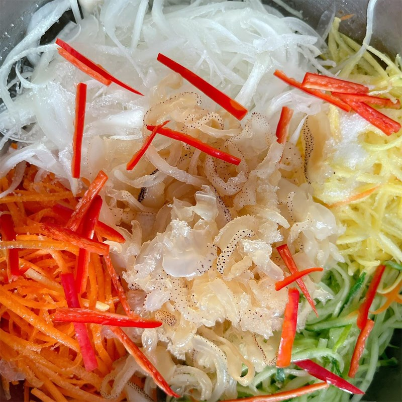 Bước 4: Trộn gỏi & nêm nếm

Cho sứa đã ráo + rau củ + xoài/hoa chuối (nếu có) vào tô lớn.

Rưới từ từ nước trộn lên, dùng đũa / muỗng trộn nhẹ nhàng theo chiều từ dưới lên trên để các nguyên liệu ngấm đều mà không bị nát.

Để gỏi “nghỉ” khoảng 3–5 phút để các vị hòa quyện.

Nêm lại nếu cần (thêm chút chanh, đường, nước mắm nếu cần).

Không nên trộn quá sớm trước khi ăn vì sứa sẽ ra nước, làm gỏi nhão và mất giòn.