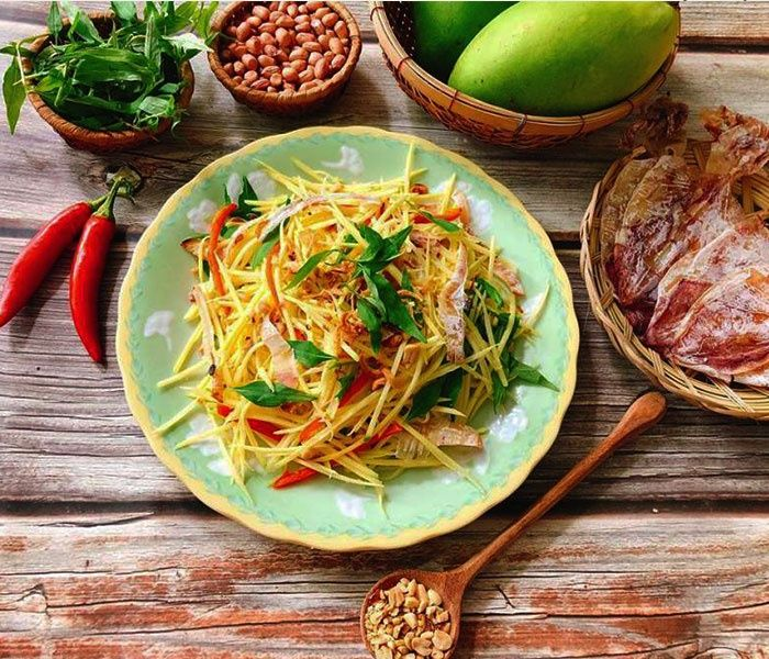 Vì sao gỏi xoài khô mực “gây nghiện”?

Gỏi xoài khô mực là món ăn kết hợp giữa hương vị tươi mát chua của xoài xanh, cùng độ dai thơm đặc trưng của khô mực, thêm chút giòn bùi của đậu phộng, điểm xuyết lên vị cay ấm từ ớt và thơm thơm của rau thơm. Sự hòa quyện cân bằng giữa các yếu tố chua – ngọt – mặn – cay – béo khiến món gỏi này dễ khiến người ăn “ghiền”, đặc biệt vào những ngày trời oi nóng, muốn ăn nhẹ mà vẫn ngon miệng.

Với nguyên liệu dễ tìm và rất dễ làm, mọi người có thể làm cho gia đình, bạn bè, đồng nghiệp 

Vậy bạn đã sẵn sàng vào bếp chưa? Yêu bếp núc sẽ “bóc tách” chi tiết từng bước, mẹo nhỏ, cách làm gỏi xoài khô mực của bạn vừa thơm ngon vừa khác biệt.