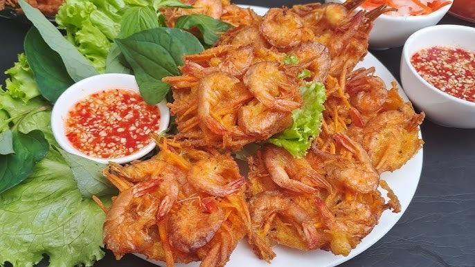 Bước 3: Trình bày và thưởng thức món bánh tép chiên khoai môn
Xếp bánh ra đĩa, nên phục vụ khi bánh còn nóng để giữ độ giòn.
Có thể kèm theo rau sống (xà lách, cải non, dưa leo) hoặc bún tươi như gợi ý của công thức.
Chuẩn bị nước chấm: nước mắm pha chua ngọt, hoặc tương ớt + mayonnaise theo khẩu vị để tăng thêm phần đậm đà.