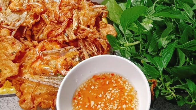 Bí quyết để bánh giòn lâu, không bị thấm dầu và ngon hơn
Để món bánh tép chiên khoai môn “ghi điểm”, bạn đừng bỏ qua những mẹo sau:
Sơ chế khoai môn kỹ: Khoai môn thường có nhựa và có thể gây ngứa khi sơ chế. Việc ngâm nước muối loãng, rửa sạch lại rất cần thiết.
Dầu chiên đủ và đúng nhiệt: Chiên ở nhiệt độ vừa phải, không quá thấp (dễ hút dầu) và không quá cao (vỏ bánh cháy trước khi nhân bên trong chín).
Không đặt hỗn hợp quá dày: Nếu bánh quá dày sẽ khó chín đều bên trong và vỏ dễ bị mềm. Nên làm phần bánh mỏng – vừa đủ muỗng.
Chiên một lớp nhỏ từng lượt: Không nên bỏ quá nhiều bánh vào chảo cùng lúc – sẽ làm giảm nhiệt dầu và bánh bị không giòn.
Thấm dầu ngay khi vớt ra: Giúp bánh không bị ỉu nhanh và giữ độ giòn lâu hơn.
Ăn ngay khi bánh còn nóng: Vỏ bánh khi nguội sẽ phần nào bị mềm, mất độ giòn ban đầu.
Đi kèm rau sống và nước chấm: Sự tươi mát của rau, vị chua – mặn – ngọt của nước chấm sẽ làm bánh thêm phần “ăn được nhiều hơn”.